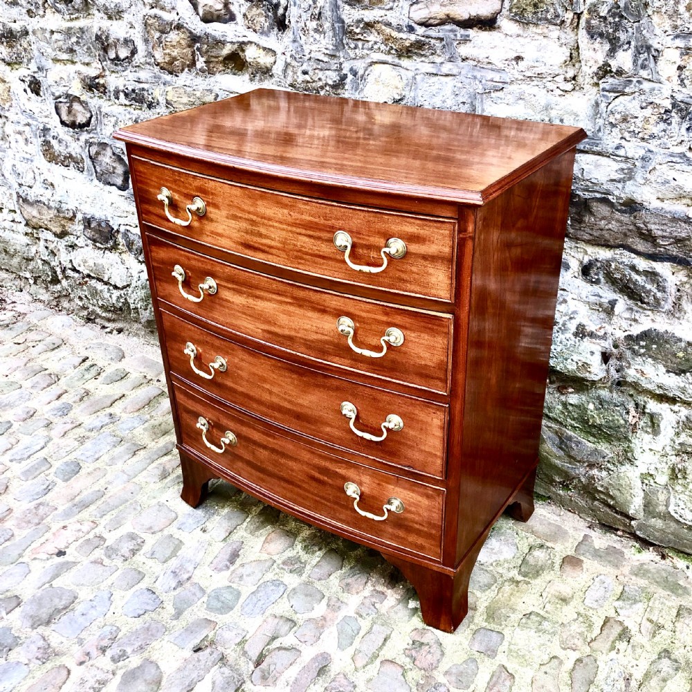 A mid-Victorian mahogany bowfront chest of drawers featuring four graduated drawers with curved fronts, brass drop handles, and bracket feet. View IV