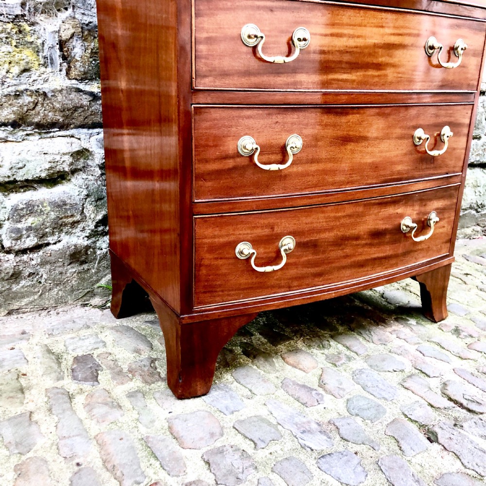 A mid-Victorian mahogany bowfront chest of drawers featuring four graduated drawers with curved fronts, brass drop handles, and bracket feet. View V