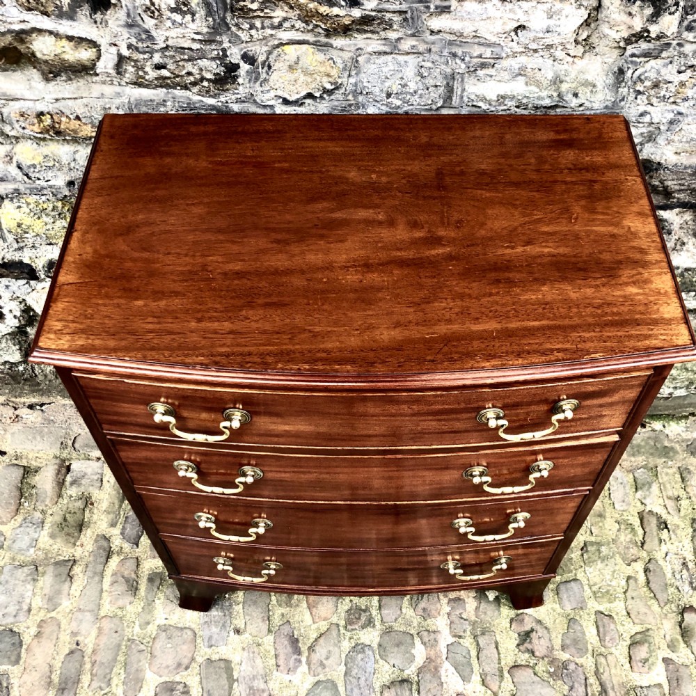 A mid-Victorian mahogany bowfront chest of drawers featuring four graduated drawers with curved fronts, brass drop handles, and bracket feet. View VI
