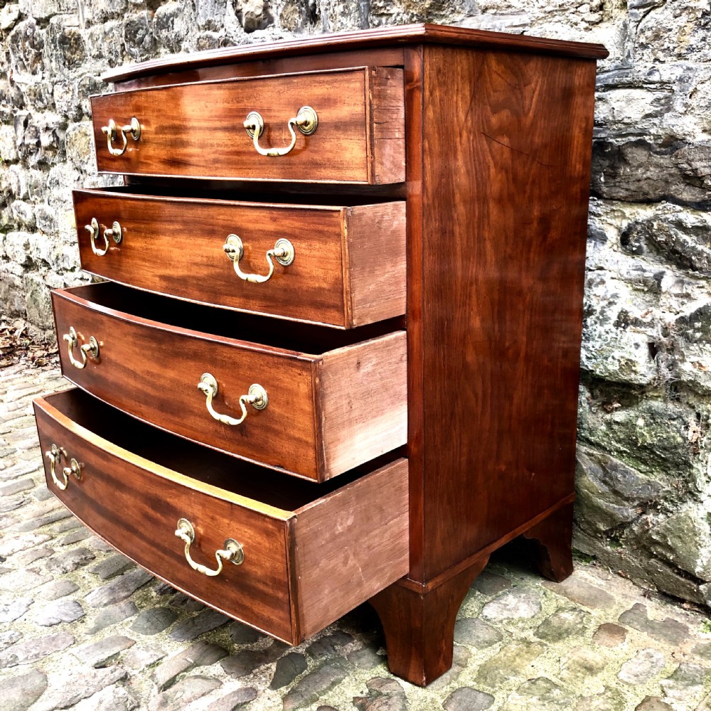 A mid-Victorian mahogany bowfront chest of drawers featuring four graduated drawers with curved fronts, brass drop handles, and bracket feet. View VII