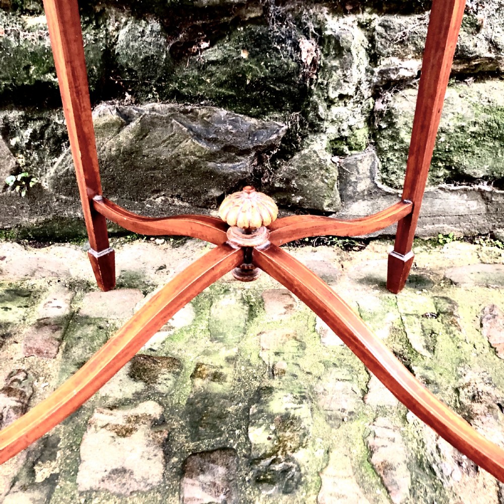 An Edwardian satinwood occasional table with a shaped top, crossbanded edging, square tapered legs, and an X-frame stretcher with a central finial. View V