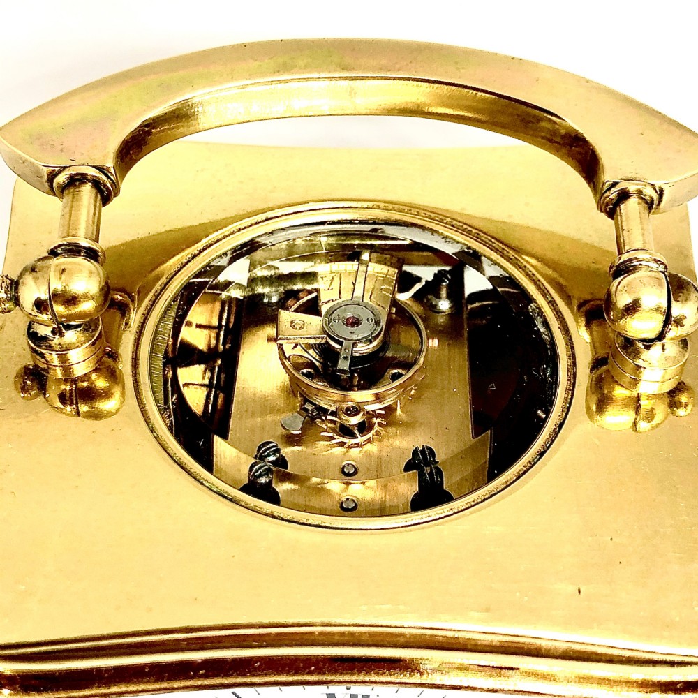 A late 19th-century French gilt brass carriage clock featuring a rectangular case with bevelled glass panels, an arched top handle, and a white enamel dial with black Roman numerals. View V