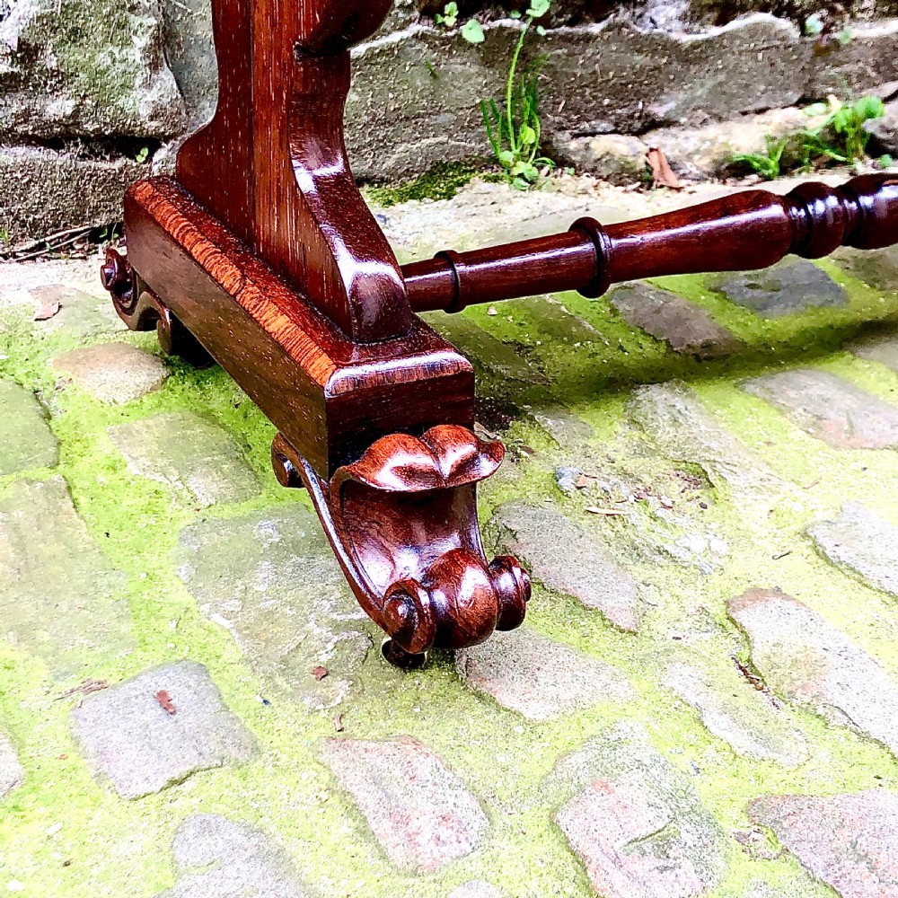 A William IV rosewood work table featuring two drawer fronts, turned knobs, keyhole escutcheons, a red fabric drop pouch, and carved end supports. View III