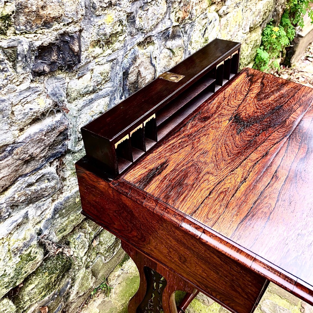 A William IV rosewood work table featuring two drawer fronts, turned knobs, keyhole escutcheons, a red fabric drop pouch, and carved end supports. View VI
