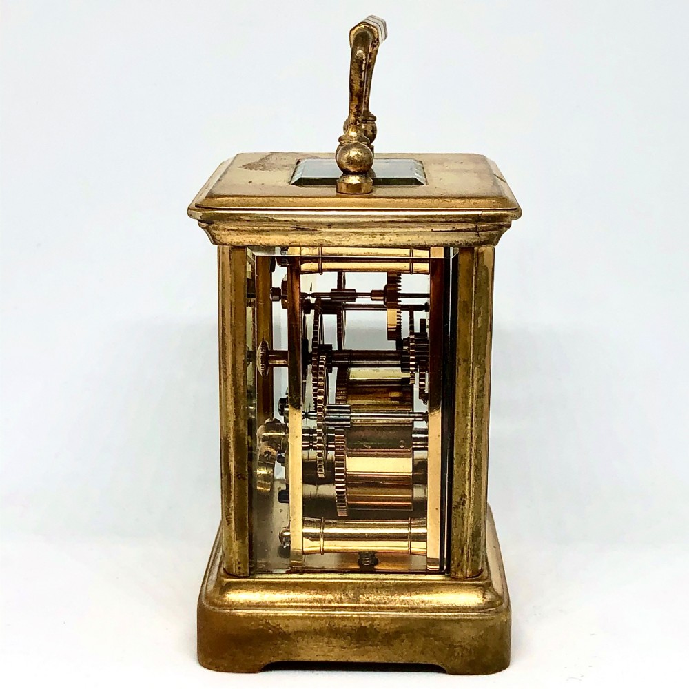 A late nineteenth-century miniature French gilt brass carriage clock featuring a rectangular case with glass panels, a curved top handle, and a white enamel dial with Roman numerals. View III