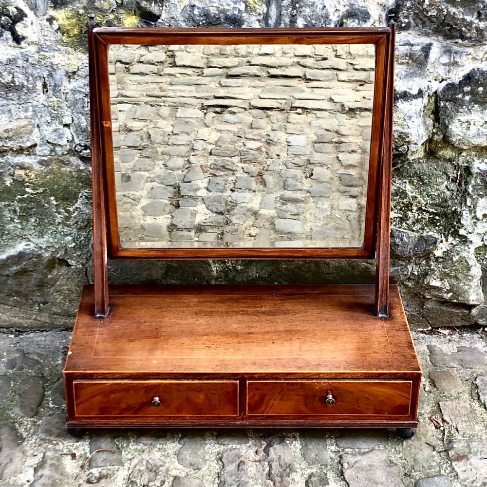 A George III mahogany dressing table mirror with a rectangular swivel glass frame set above a two-drawer base.