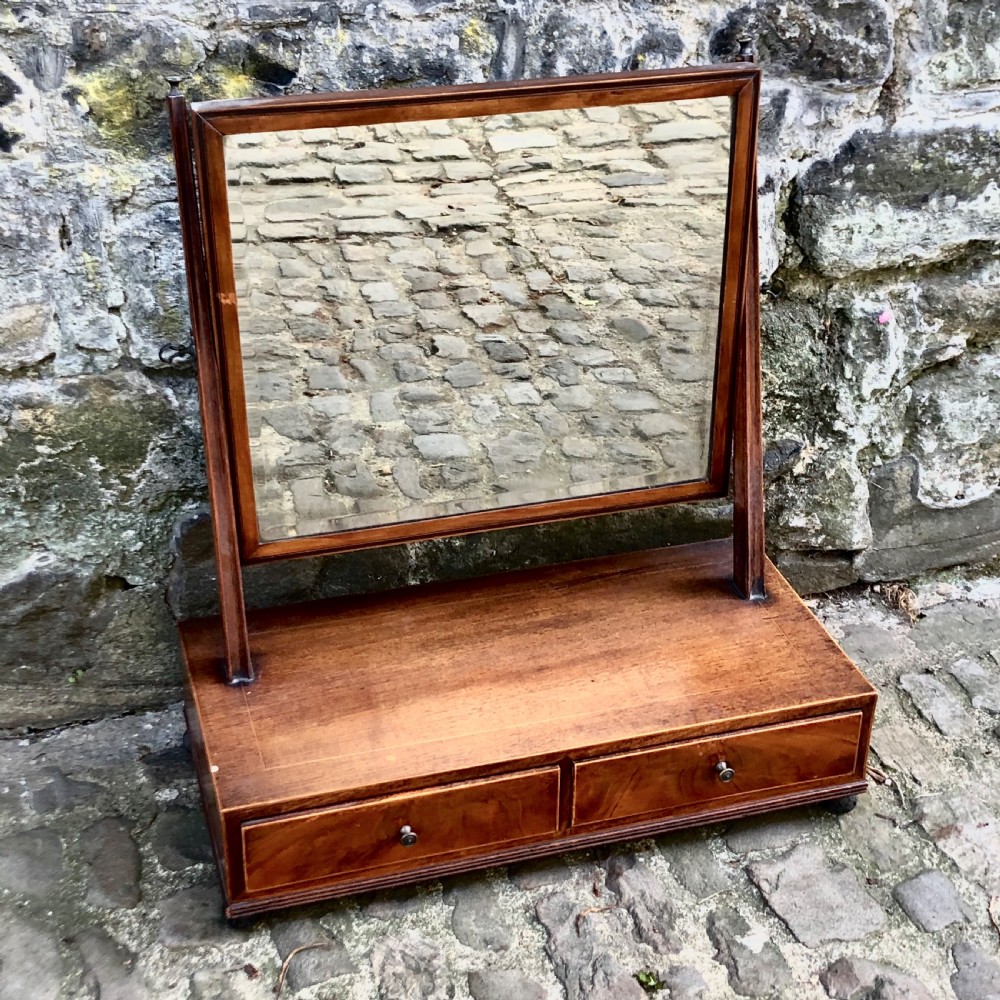 A George III mahogany dressing table mirror with a rectangular swivel glass frame set above a two-drawer base. View II