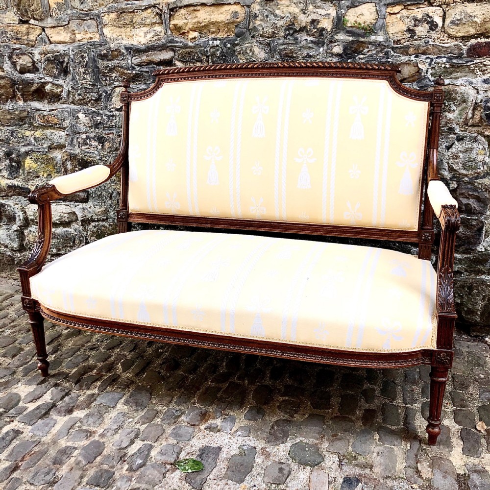 A French Second Empire carved walnut sofa featuring a cream and pale yellow striped upholstered back and seat with padded armrests and fluted legs. View VII