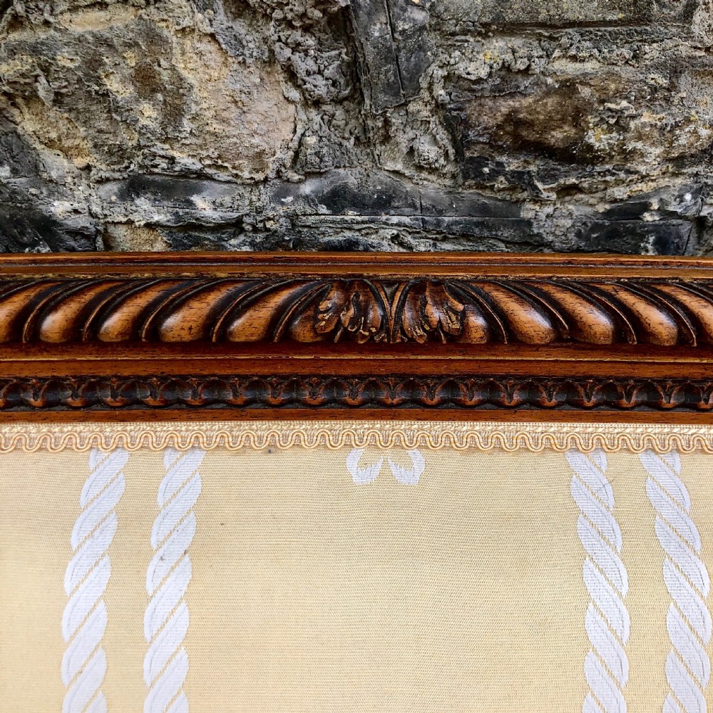 A French Second Empire carved walnut sofa featuring a cream and pale yellow striped upholstered back and seat with padded armrests and fluted legs. View VIII
