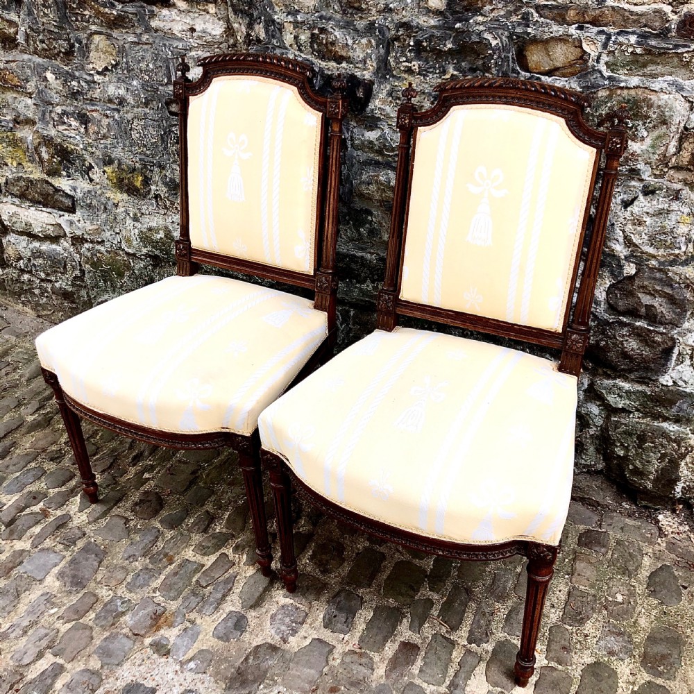 A pair of antique French Second Empire carved walnut side chairs upholstered in a cream patterned damask fabric featuring fluted legs. View II