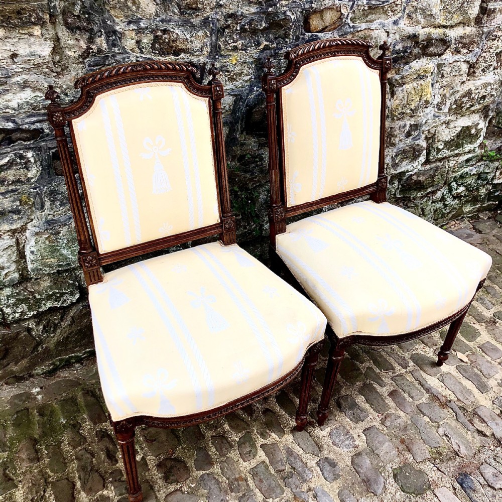 A pair of antique French Second Empire carved walnut side chairs upholstered in a cream patterned damask fabric featuring fluted legs. View III