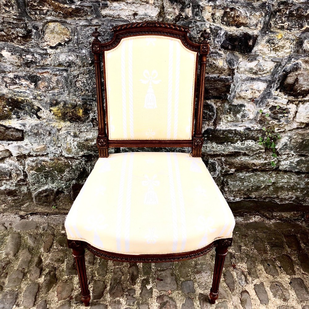 A pair of antique French Second Empire carved walnut side chairs upholstered in a cream patterned damask fabric featuring fluted legs. View IV