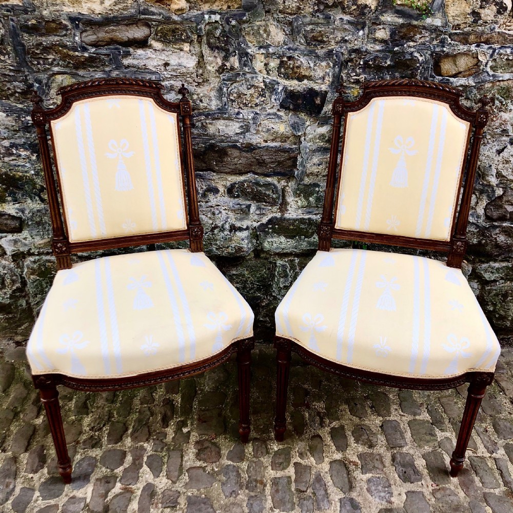 A pair of antique French Second Empire carved walnut side chairs upholstered in a cream patterned damask fabric featuring fluted legs. View IX