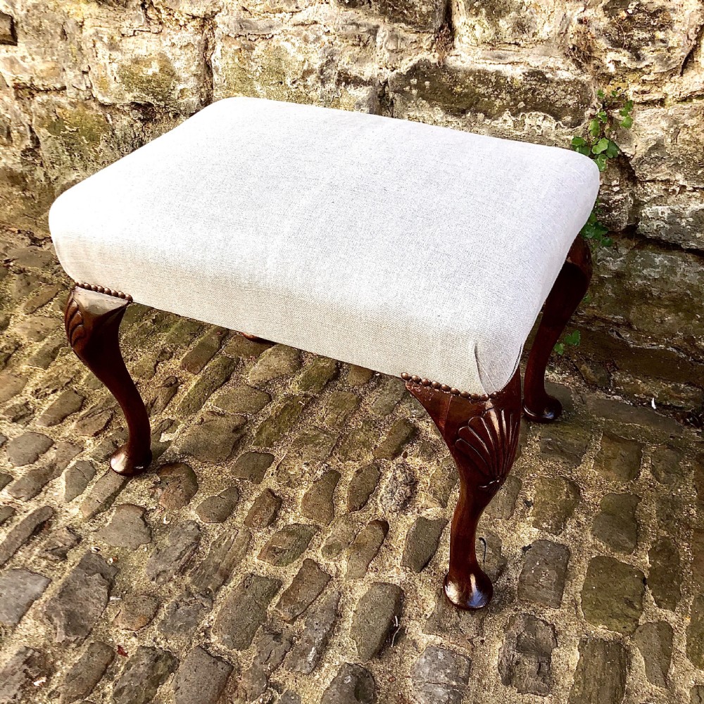 A 19th-century walnut dressing table stool featuring carved cabriole legs with shell knee detailing, brass studded trim, and a cream upholstered linen cushion. View II