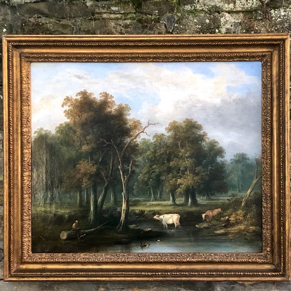 A late 18th-century oil painting on canvas depicting a rural landscape with cattle standing in a stream, surrounded by mature trees, housed in a moulded giltwood frame.