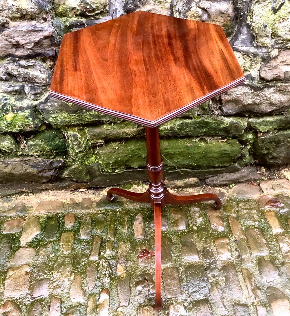 A late 19th-century mahogany wine table featuring a polished hexagonal top, turned central pedestal column, and three-legged tripod base.