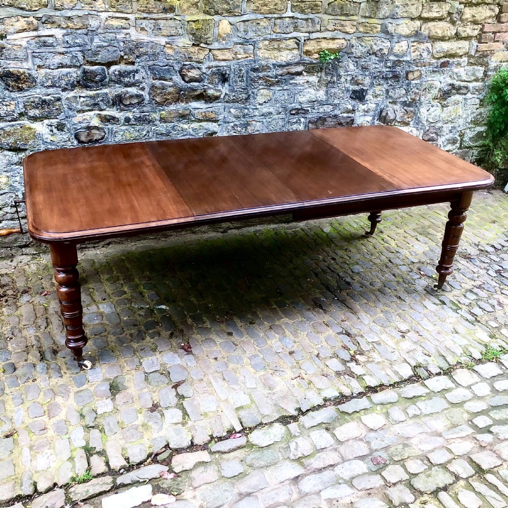 A mid Victorian mahogany extending dining table with additional leaves, turned legs, and porcelain castors.