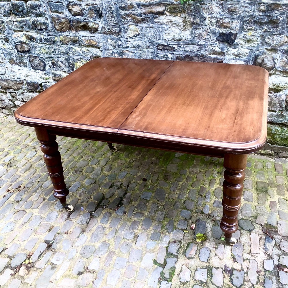 A mid Victorian mahogany extending dining table with additional leaves, turned legs, and porcelain castors. View II