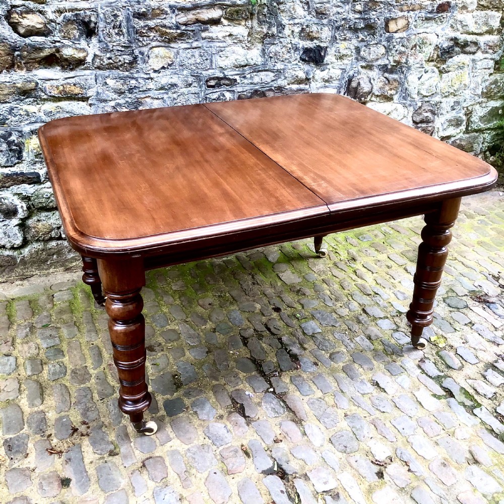 A mid Victorian mahogany extending dining table with additional leaves, turned legs, and porcelain castors. View III
