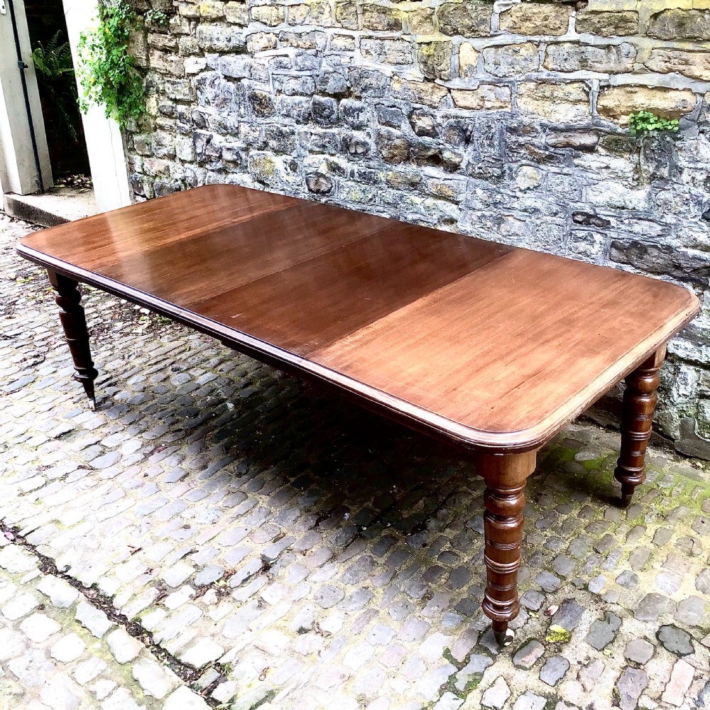 A mid Victorian mahogany extending dining table with additional leaves, turned legs, and porcelain castors. View IV