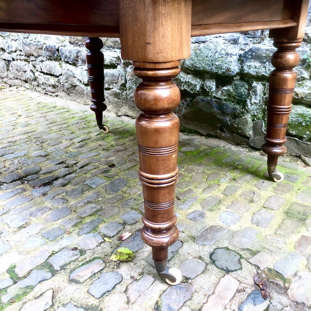A mid Victorian mahogany extending dining table with additional leaves, turned legs, and porcelain castors. View VI