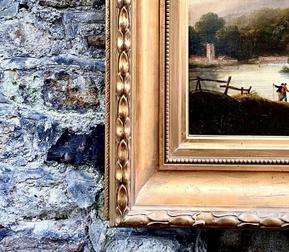 An early nineteenth-century oil painting depicting Tintern Abbey beside a river, surrounded by mountains and set within a carved gold frame. View III