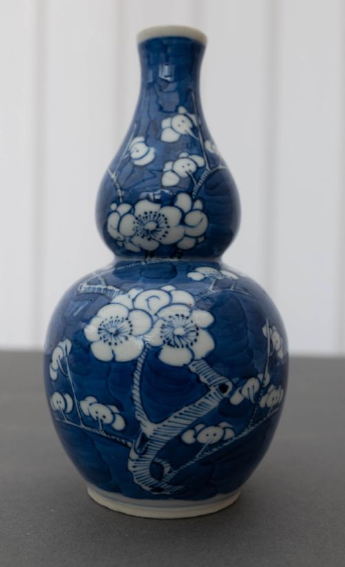 fig 1. A double gourd-shaped Chinese porcelain vase decorated with white prunus blossom patterns over a dark cobalt blue background.