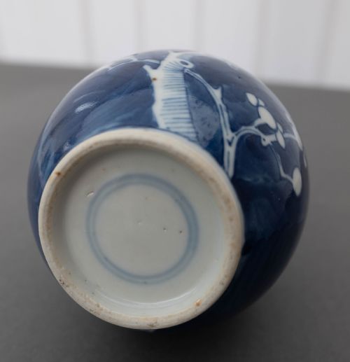 fig 1. A Chinese porcelain bottle vase featuring a slender neck and globular body decorated with white plum blossom motifs against a cobalt blue background.