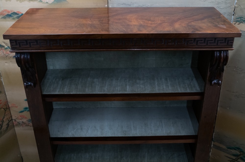 A dark mahogany open bookcase featuring four shelves, a carved Greek key pattern along the top frieze, and carved side corbels. View V