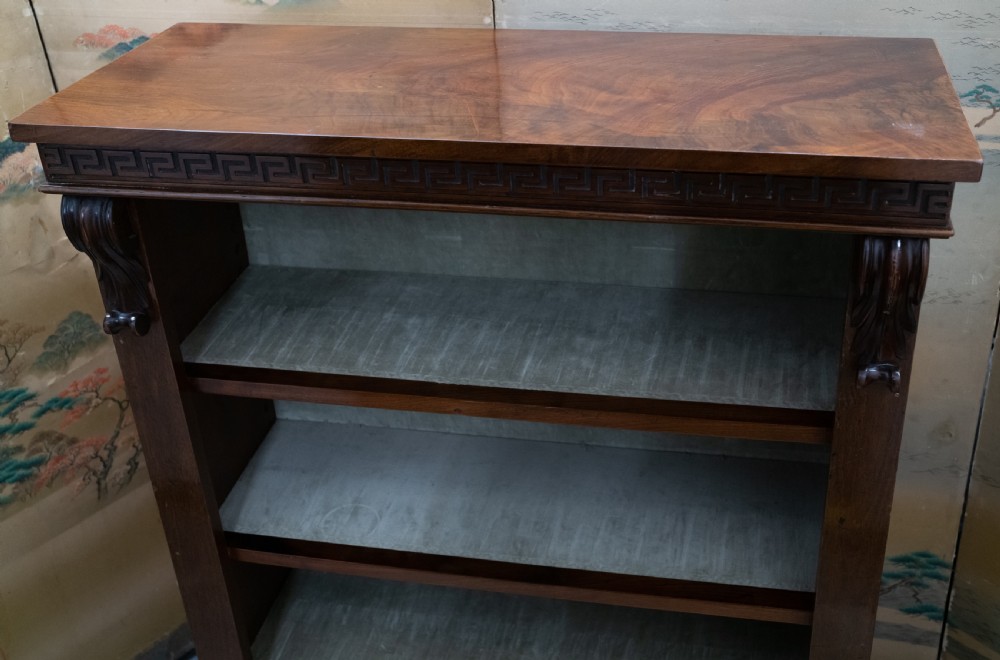 A dark mahogany open bookcase featuring four shelves, a carved Greek key pattern along the top frieze, and carved side corbels. View VI