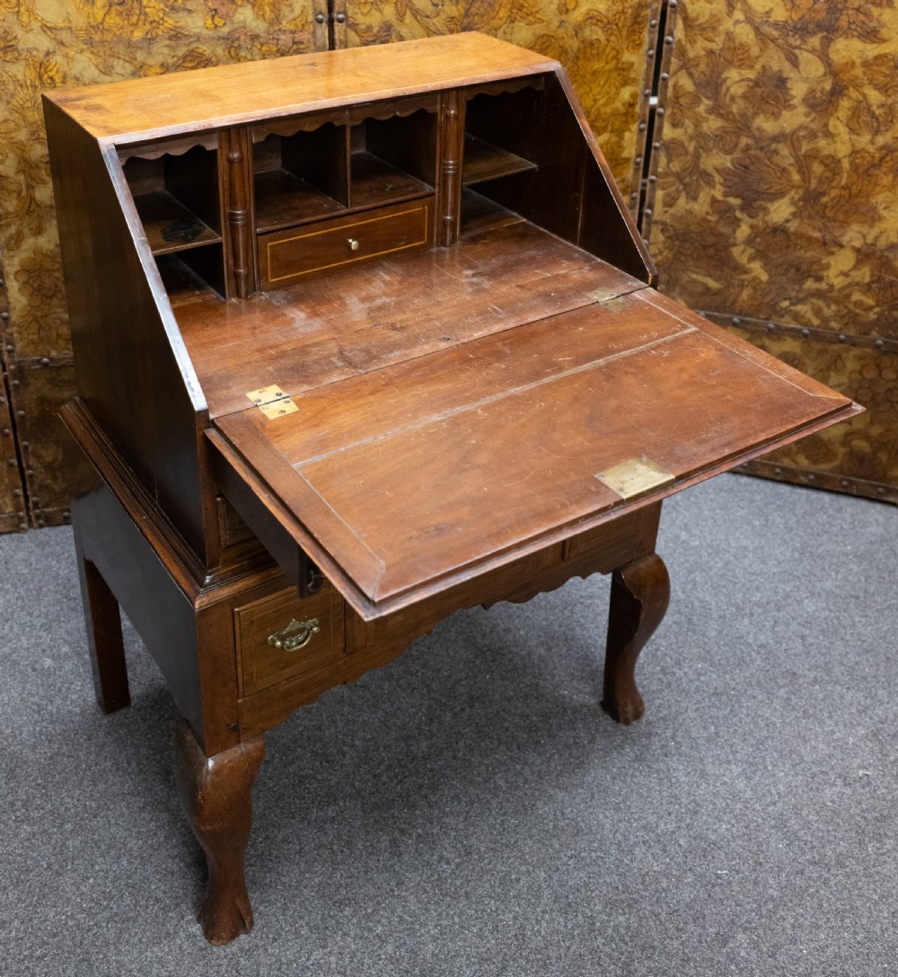 A small solid walnut slant-front bureau featuring a drop-down flap, multiple drawers with brass handles, and cabriole legs. View VI