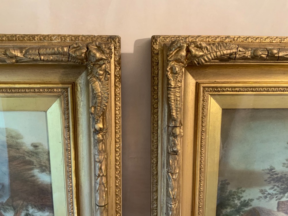 A pair of nineteenth-century mezzotint prints depicting pastoral landscape and cottage scenes, displayed in rectangular giltwood frames with gold slip mounts. View XI