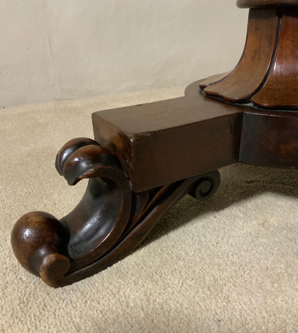 An antique mahogany writing table featuring a rectangular top with rounded corners, a deep frieze, and thick turned legs resting on carved paw feet. View V