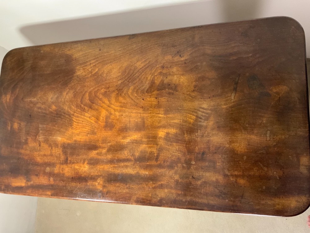 An antique mahogany writing table featuring a rectangular top with rounded corners, a deep frieze, and thick turned legs resting on carved paw feet. View VI