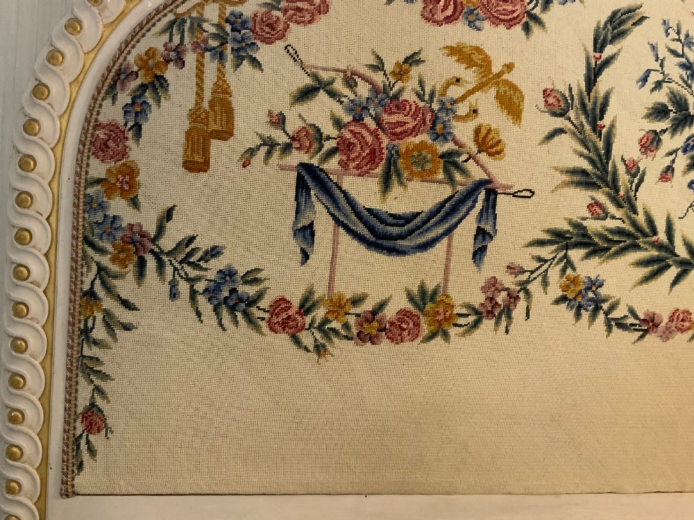 A carved cream painted and parcel gilt five-foot bed frame featuring a arched floral tapestry upholstered headboard and fluted footboard. View VIII