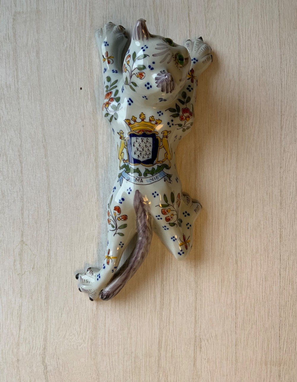A pair of hand-painted tin-glazed ceramic cat wall pockets styled in recumbent poses with heraldic coat of arms motifs and green glass eyes. View VII