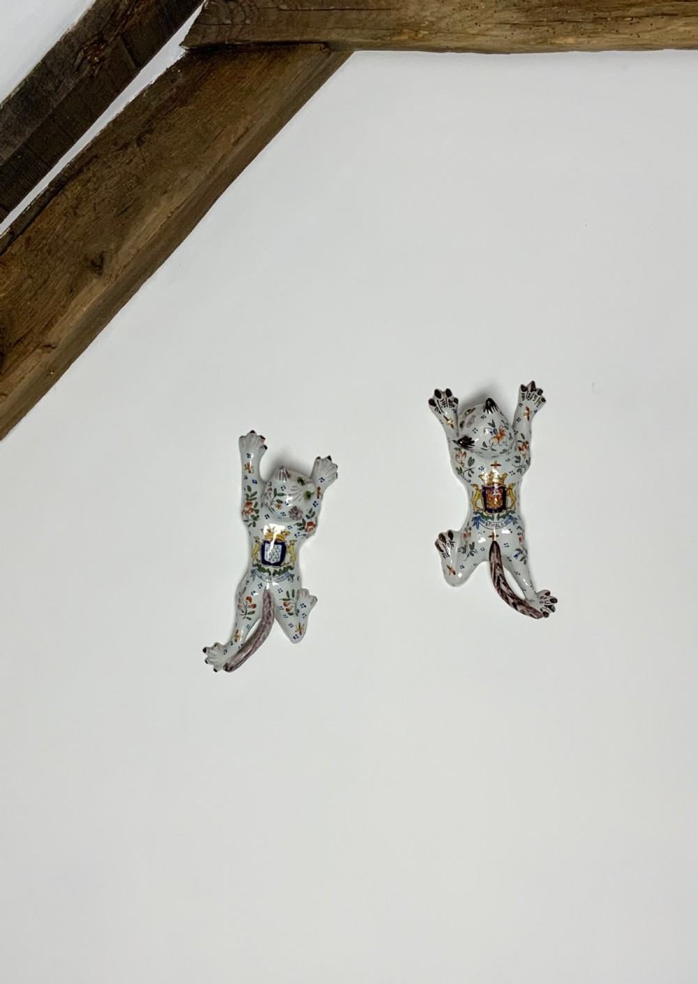 A pair of hand-painted tin-glazed ceramic cat wall pockets styled in recumbent poses with heraldic coat of arms motifs and green glass eyes. View VIII