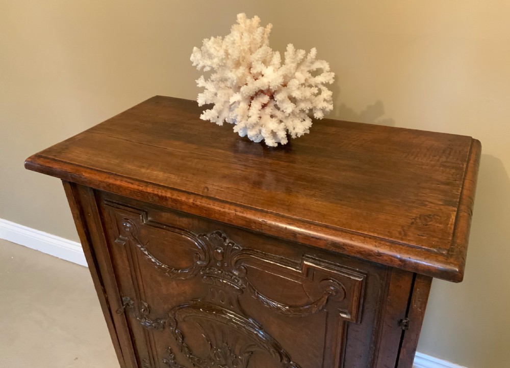 An Italian walnut Baroque cabinet featuring a single door decorated with relief carvings of an urn and floral garlands on a moulded plinth base. View IX