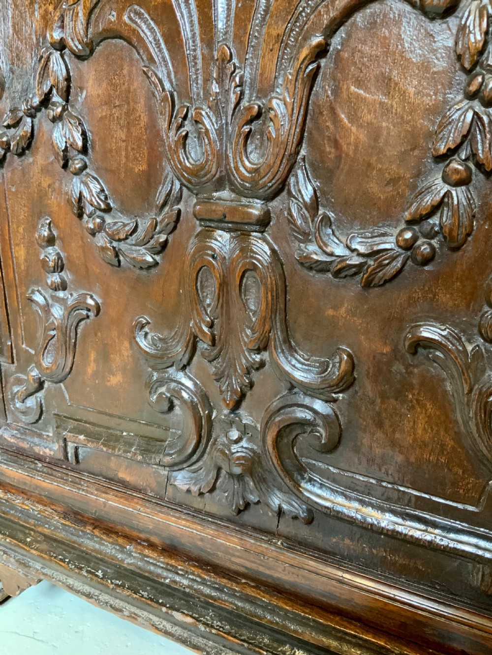 An Italian walnut Baroque cabinet featuring a single door decorated with relief carvings of an urn and floral garlands on a moulded plinth base. View XII