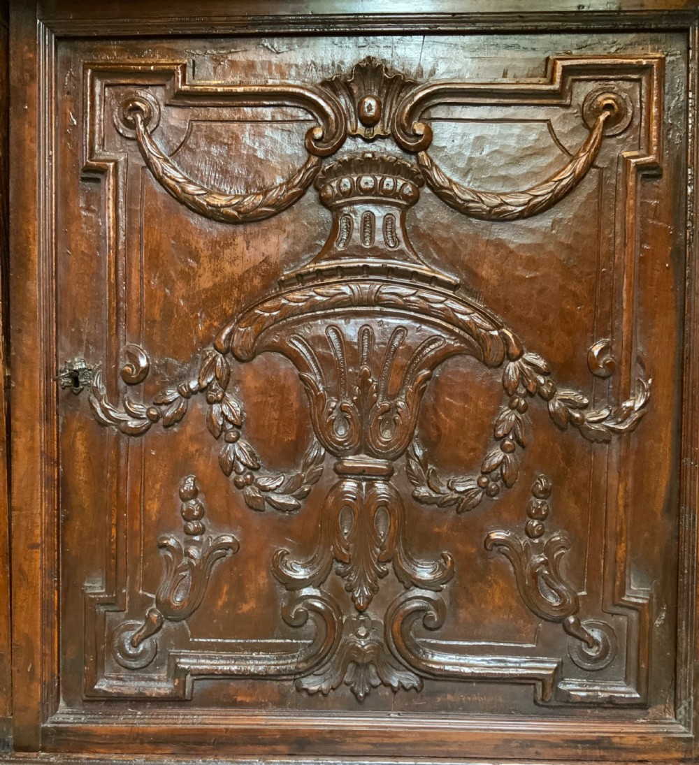 An Italian walnut Baroque cabinet featuring a single door decorated with relief carvings of an urn and floral garlands on a moulded plinth base. View XIII