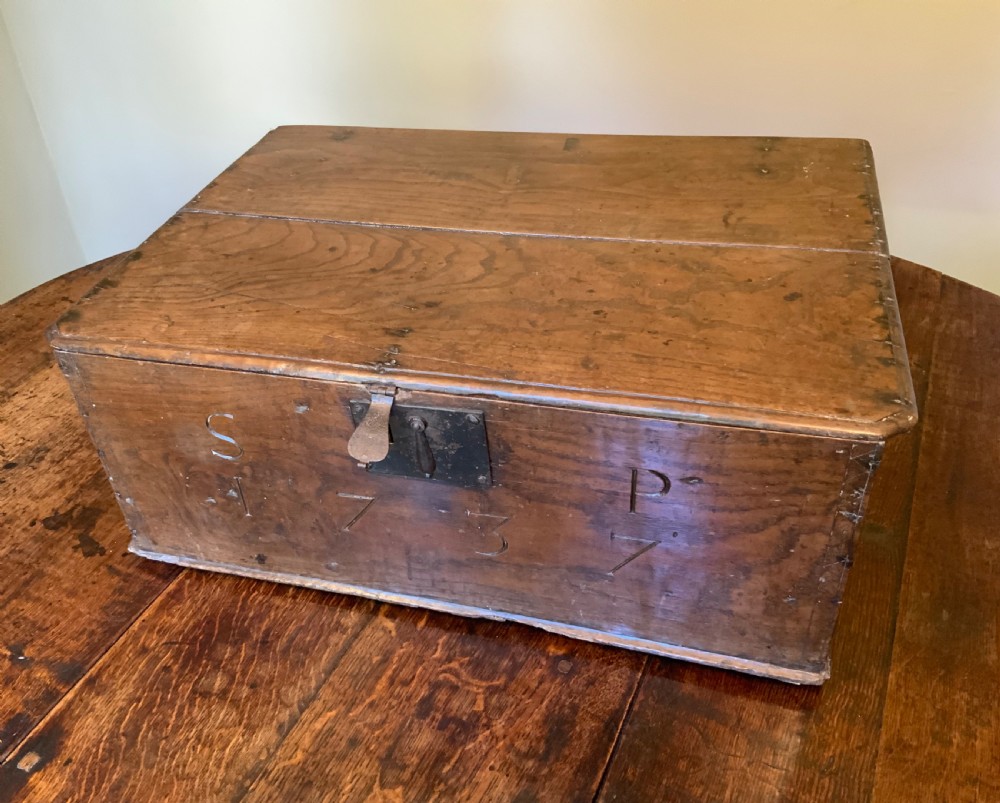 A rectangular warm brown elm bible box with carved initials S and P, dated 1737, featuring a central iron lock plate.