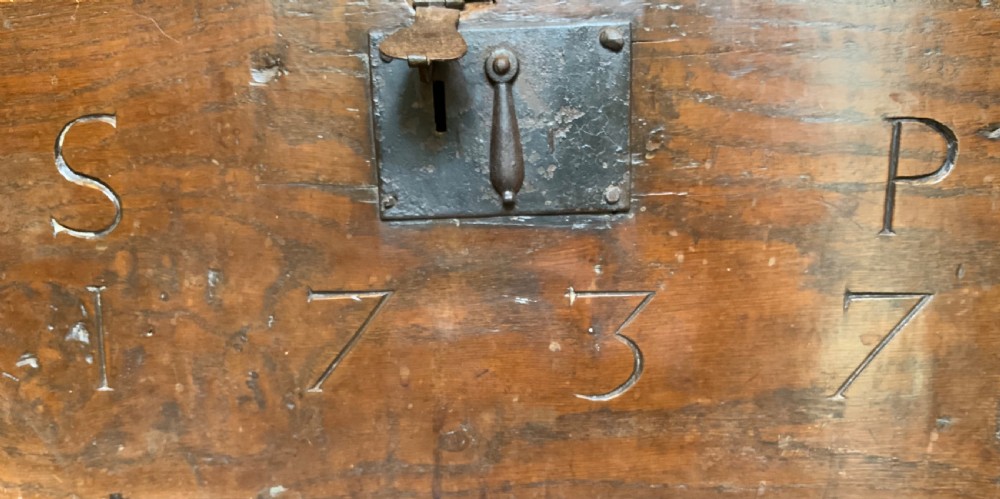 A rectangular warm brown elm bible box with carved initials S and P, dated 1737, featuring a central iron lock plate. View V
