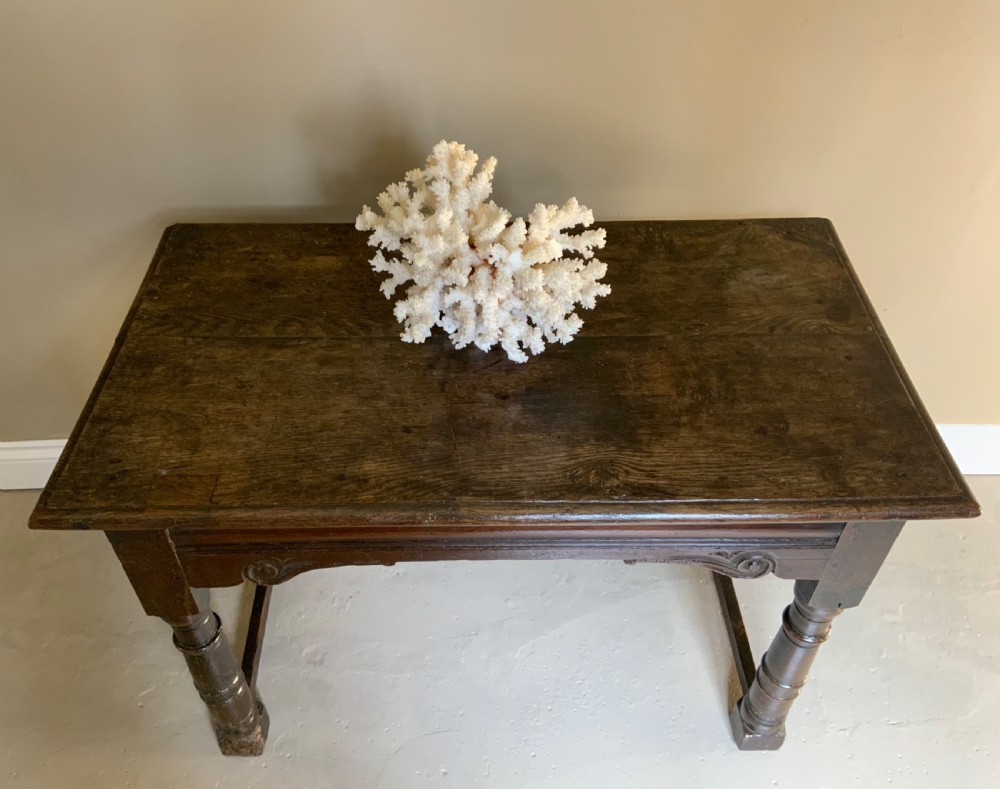 A 17th-century dark oak side table featuring turned legs, carved scroll spandrels, and lower stretcher rails. View IV