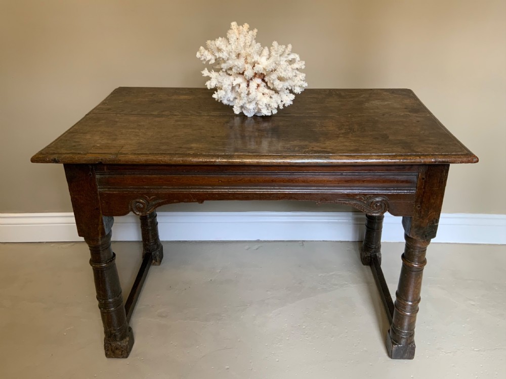 A 17th-century dark oak side table featuring turned legs, carved scroll spandrels, and lower stretcher rails. View VI