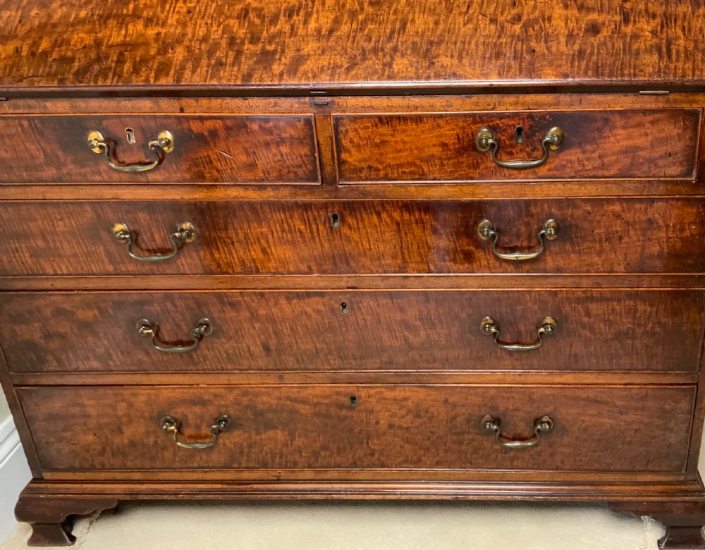 A George III mahogany bureau featuring a sloping front flap over four graduated drawers with brass swan-neck handles and bracket feet. View XIV