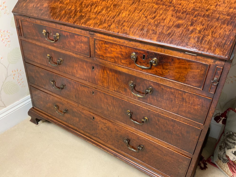 A George III mahogany bureau featuring a sloping front flap over four graduated drawers with brass swan-neck handles and bracket feet. View III