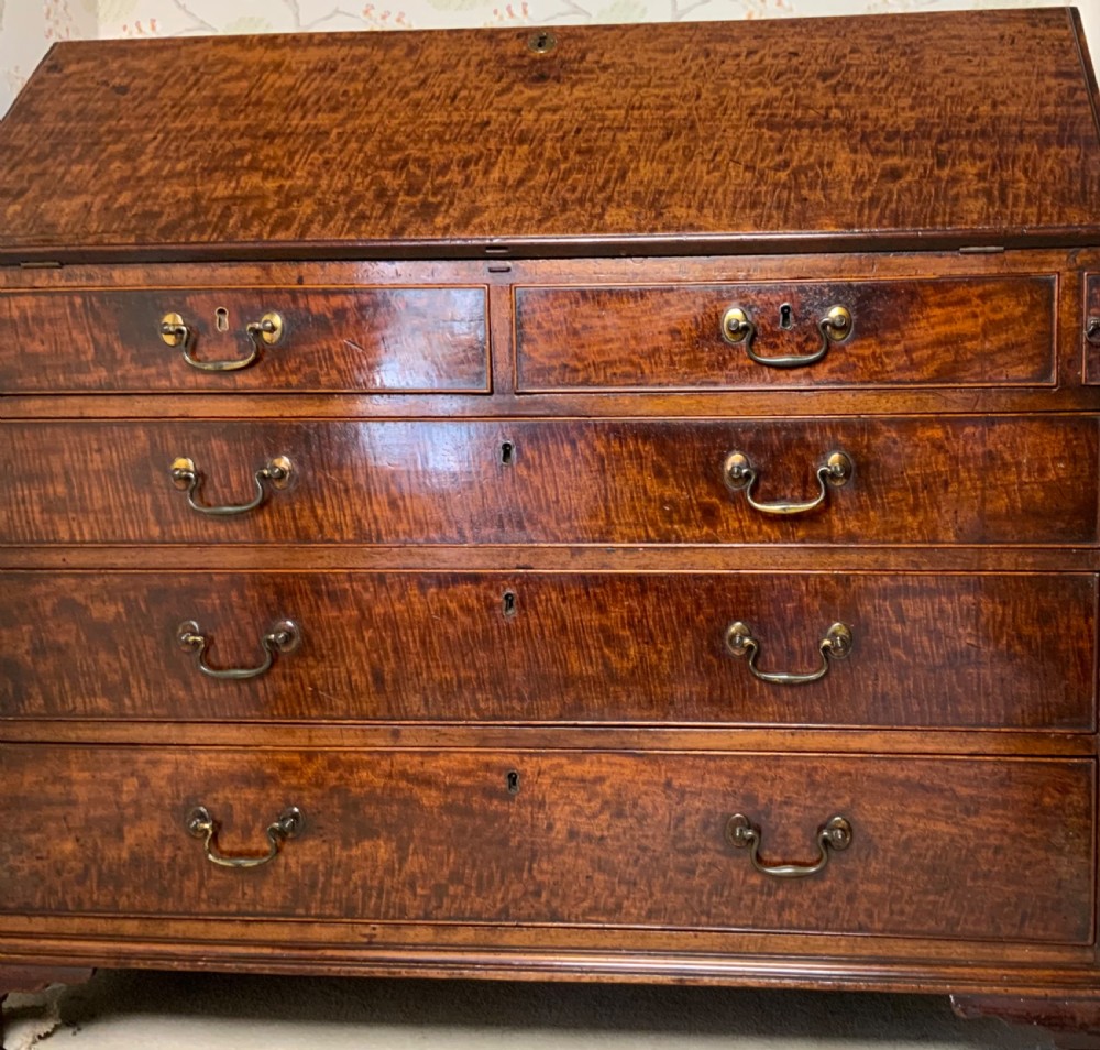 A George III mahogany bureau featuring a sloping front flap over four graduated drawers with brass swan-neck handles and bracket feet. View V