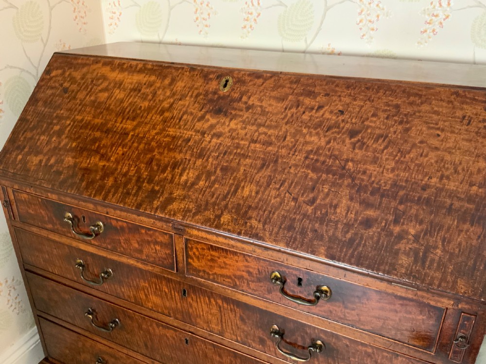 A George III mahogany bureau featuring a sloping front flap over four graduated drawers with brass swan-neck handles and bracket feet. View VII