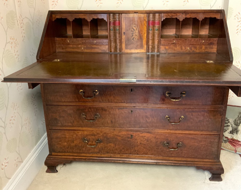 A George III mahogany bureau featuring a sloping front flap over four graduated drawers with brass swan-neck handles and bracket feet. View VIII