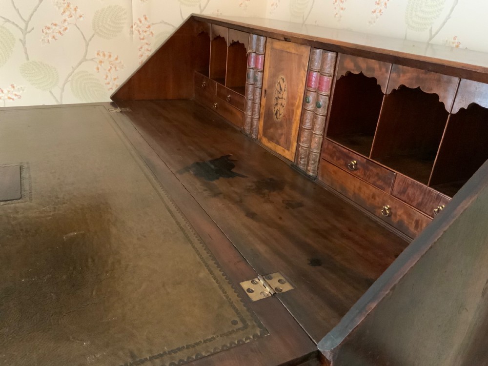 A George III mahogany bureau featuring a sloping front flap over four graduated drawers with brass swan-neck handles and bracket feet. View IX